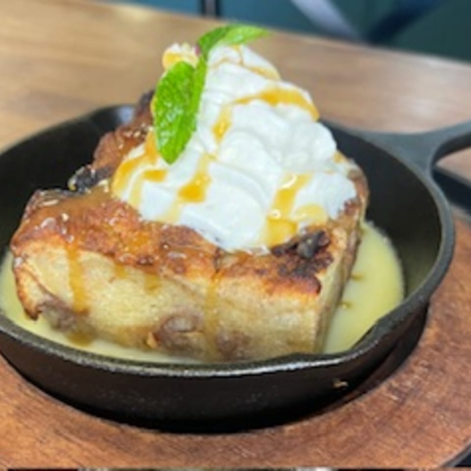 Max & Louie's French toast in a skillet, topped with whipped cream, caramel, and mint.