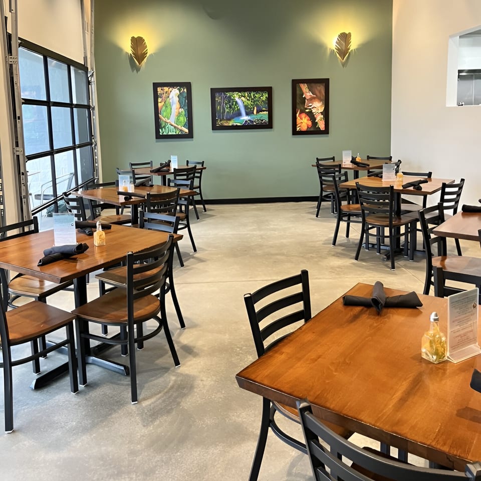 Max & Louie's dining room with wooden tables, black chairs, and nature-themed art on green walls.